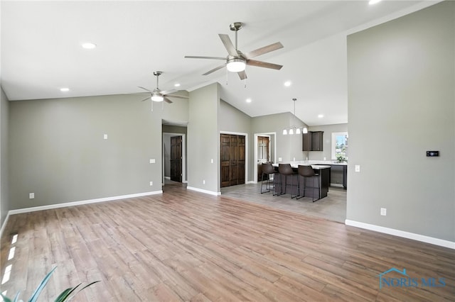 unfurnished living room with ceiling fan, recessed lighting, high vaulted ceiling, and light wood-style flooring
