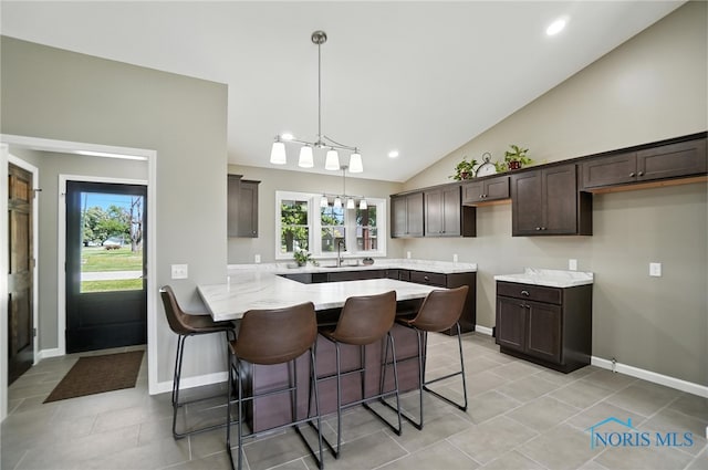 kitchen with a peninsula, dark brown cabinets, a kitchen breakfast bar, lofted ceiling, and a chandelier