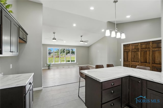 kitchen with a kitchen breakfast bar, recessed lighting, a ceiling fan, vaulted ceiling, and light stone counters