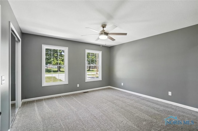 carpeted spare room with ceiling fan and baseboards