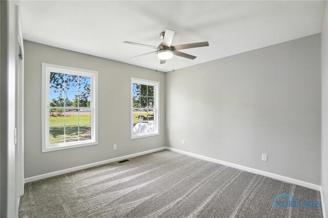 carpeted spare room with ceiling fan and baseboards