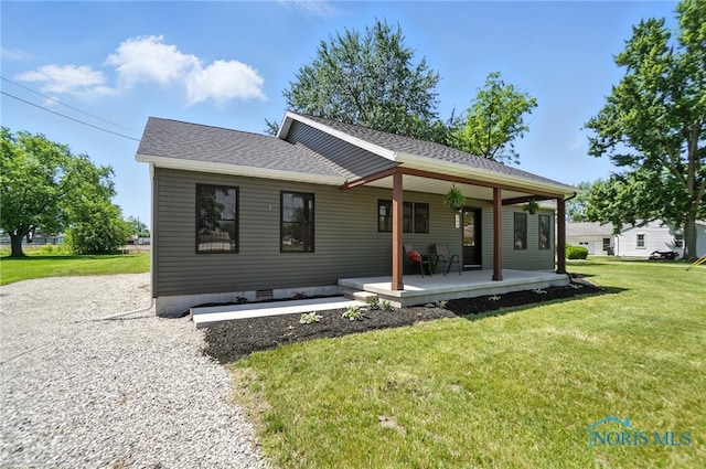 back of property with a yard, a porch, and roof with shingles