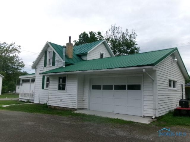 530 N Taft Ave, Ottawa, OH 45875 - view of side of home featuring driveway, a metal roof, a chimney, and a garage