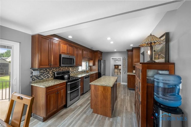 855 Strotz Dr, Toledo, OH 43612 - kitchen featuring appliances with stainless steel finishes, light wood-type flooring, backsplash, light stone counters, and a kitchen island