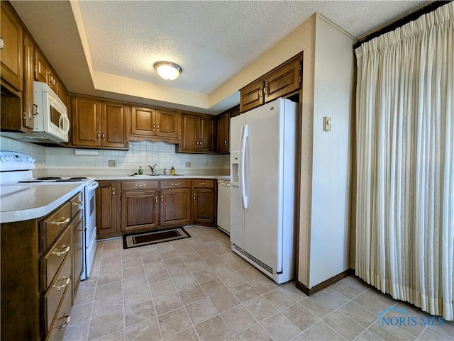 209 Hawthorn Dr, Archbold, OH 43502 - kitchen with white appliances, a textured ceiling, light countertops, backsplash, and brown cabinetry