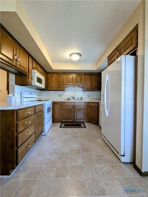 209 Hawthorn Dr, Archbold, OH 43502 - kitchen featuring white appliances, a textured ceiling, light countertops, and brown cabinetry