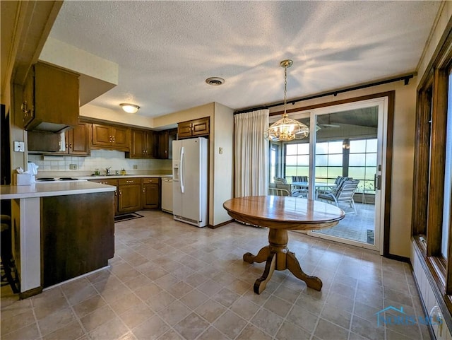 209 Hawthorn Dr, Archbold, OH 43502 - kitchen with white refrigerator with ice dispenser, light countertops, a chandelier, a textured ceiling, and dishwashing machine