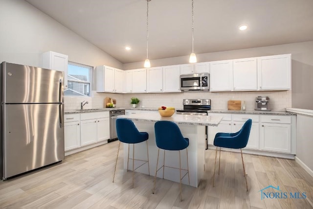 1515 Lee Ann Ave, Defiance, OH 43512 - kitchen featuring appliances with stainless steel finishes, white cabinets, decorative backsplash, a kitchen breakfast bar, and a center island