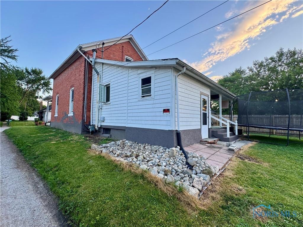 310 Hopkins St, Defiance, OH 43512 - view of side of property featuring a trampoline, entry steps, and brick siding