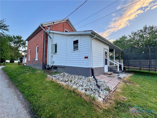 310 Hopkins St, Defiance, OH 43512 - view of side of property featuring a trampoline, entry steps, and brick siding