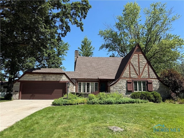 610 E High St, Defiance, OH 43512 - english style home with stone siding, a garage, a front lawn, driveway, and a chimney