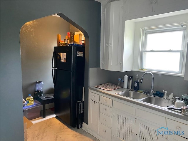 2615 Greenway St, Toledo, OH 43607 - kitchen featuring freestanding refrigerator, arched walkways, white cabinets, light marble finish flooring, and light countertops