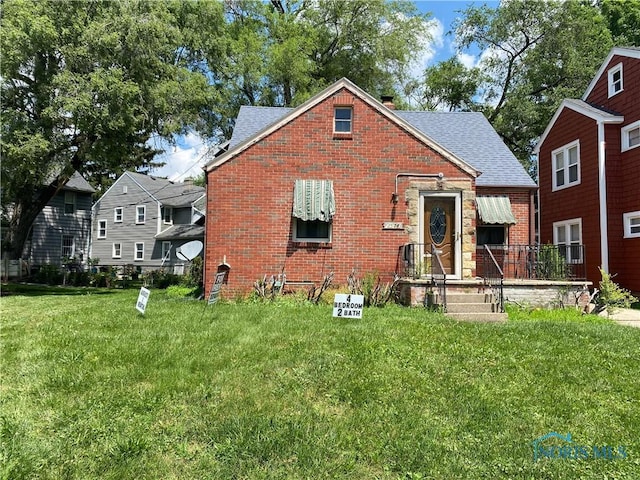2534 Montebello Rd, Toledo, OH 43607 - view of front of house with brick siding, a front lawn, and roof with shingles