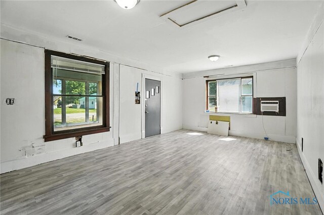 709 W Jackson St, Paulding, OH 45879 - unfurnished living room featuring healthy amount of natural light, wood finished floors, cooling unit, and attic access