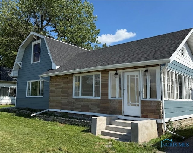 335 E N St, Mcclure, OH 43534 - view of front of house featuring entry steps, a front lawn, a shingled roof, and a sunroom