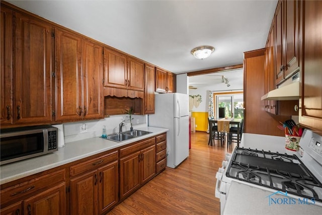 2958 Penrose Ave, Toledo, OH 43614 - kitchen with white appliances, under cabinet range hood, light wood-style floors, light countertops, and brown cabinetry