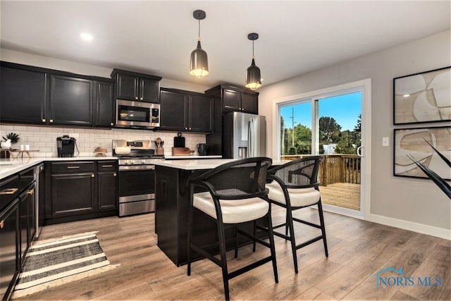 1492 Lee Ann Ave, Defiance, OH 43512 - kitchen featuring stainless steel appliances, dark cabinetry, a breakfast bar, backsplash, and light countertops