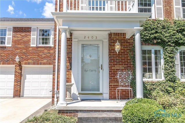 2403 Hempstead Rd, Ottawa Hills, OH 43606 - property entrance featuring brick siding, a garage, driveway, and a balcony