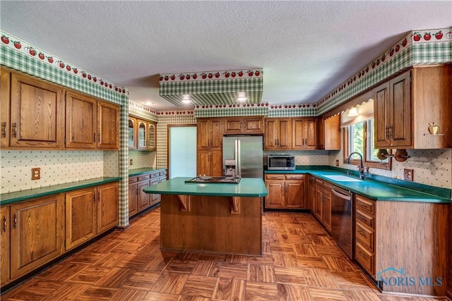 6608 Inglewood Dr, Holland, OH 43528 - kitchen with appliances with stainless steel finishes, wallpapered walls, brown cabinets, a center island, and a textured ceiling