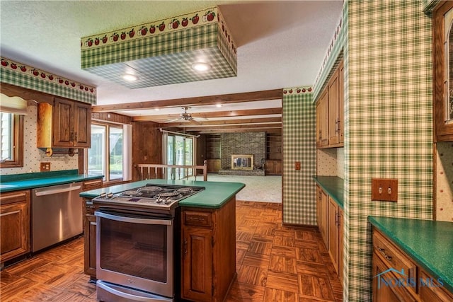 6608 Inglewood Dr, Holland, OH 43528 - kitchen featuring stainless steel appliances, wallpapered walls, dark countertops, a fireplace, and a center island