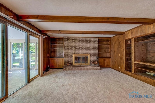 6608 Inglewood Dr, Holland, OH 43528 - unfurnished living room featuring wooden walls, beam ceiling, carpet flooring, a textured ceiling, and a fireplace