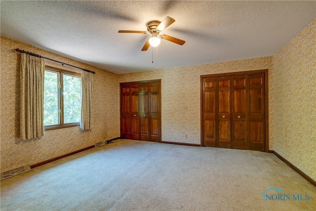6608 Inglewood Dr, Holland, OH 43528 - unfurnished bedroom featuring light colored carpet, wallpapered walls, a textured ceiling, and ceiling fan