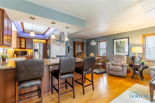 312 W Dudley St, Maumee, OH 43537 - kitchen with appliances with stainless steel finishes, island exhaust hood, glass insert cabinets, light wood-style flooring, and a textured ceiling