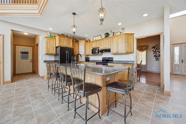 586 N State Route 587, Fostoria, OH 44830 - kitchen with black appliances, light tile patterned floors, under cabinet range hood, a breakfast bar, and recessed lighting