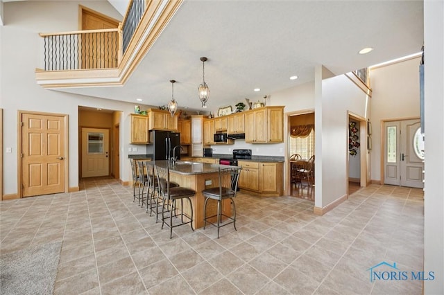586 N State Route 587, Fostoria, OH 44830 - kitchen featuring black appliances, dark countertops, a kitchen bar, a kitchen island with sink, and recessed lighting