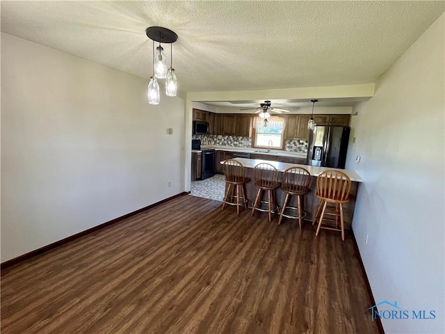 17988 Rd 156, Paulding, OH 45879 - kitchen with stainless steel appliances, dark wood-style floors, a kitchen breakfast bar, a peninsula, and decorative light fixtures