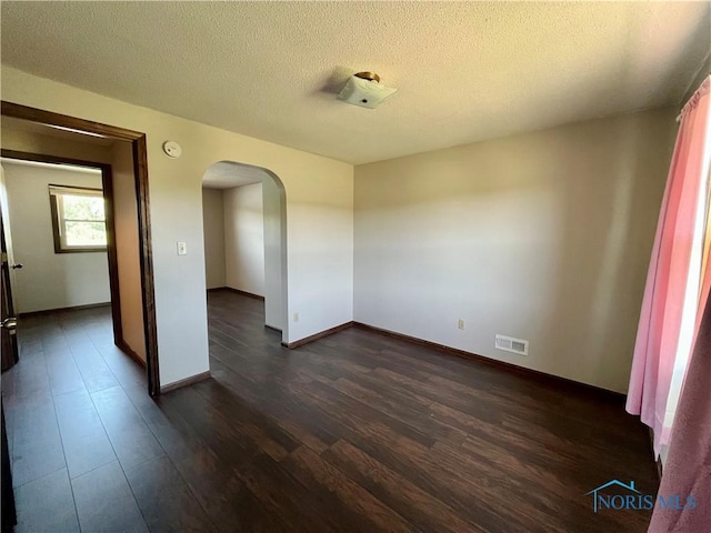 17988 Rd 156, Paulding, OH 45879 - empty room featuring arched walkways, dark wood-type flooring, a textured ceiling, and a smoke detector