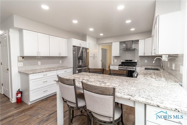 6842 Shieldwood Rd, Toledo, OH 43617 - kitchen with appliances with stainless steel finishes, wall chimney exhaust hood, tasteful backsplash, a peninsula, and light stone countertops