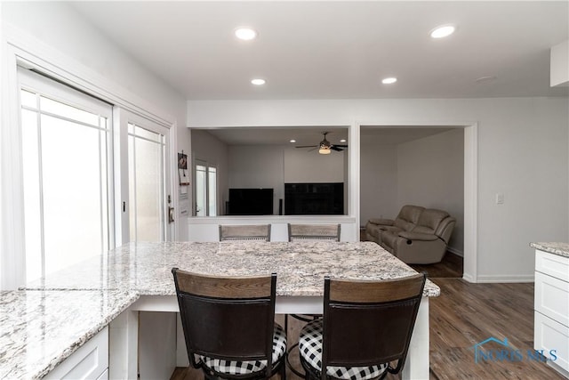 6842 Shieldwood Rd, Toledo, OH 43617 - kitchen featuring ceiling fan, dark wood-type flooring, a kitchen breakfast bar, light stone countertops, and recessed lighting