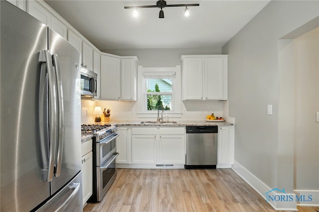 233 E 5th St, Perrysburg, OH 43551 - kitchen with appliances with stainless steel finishes, tasteful backsplash, light wood-style flooring, white cabinetry, and light stone countertops