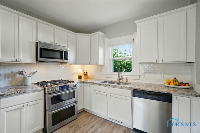 233 E 5th St, Perrysburg, OH 43551 - kitchen with stainless steel appliances, white cabinets, light wood-type flooring, tasteful backsplash, and light stone countertops