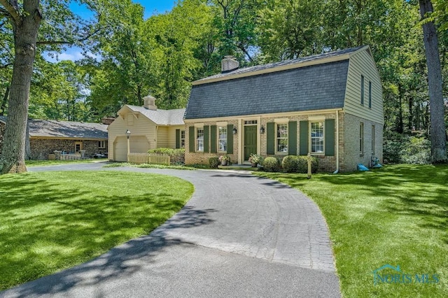 5941 Indian Trl, Sylvania, OH 43560 - colonial inspired home featuring a gambrel roof, driveway, an attached garage, a chimney, and brick siding