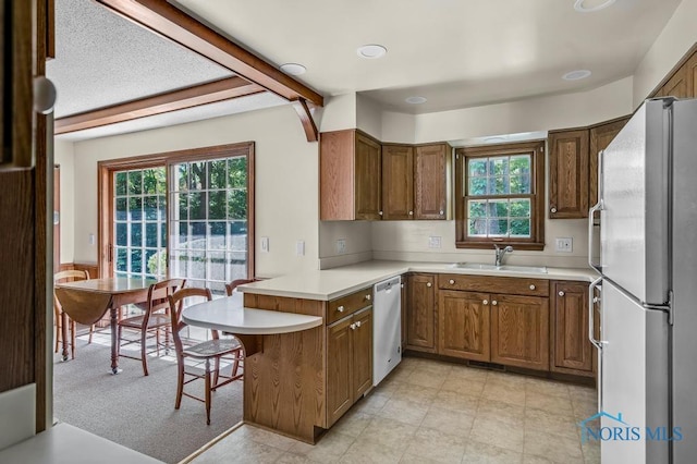 5941 Indian Trl, Sylvania, OH 43560 - kitchen featuring freestanding refrigerator, a peninsula, dishwasher, light countertops, and brown cabinetry