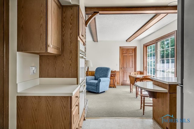 5941 Indian Trl, Sylvania, OH 43560 - kitchen with beam ceiling, light carpet, a textured ceiling, brown cabinets, and light countertops