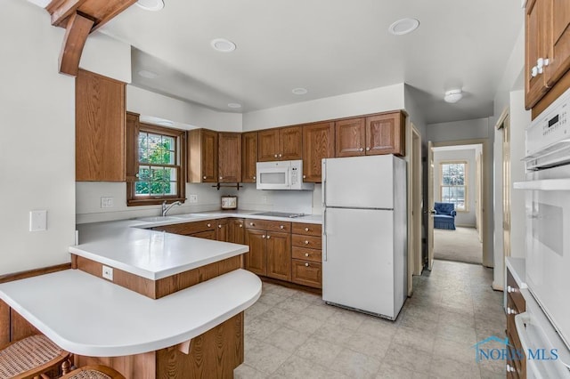 5941 Indian Trl, Sylvania, OH 43560 - kitchen with white appliances, brown cabinets, a peninsula, a breakfast bar area, and light countertops
