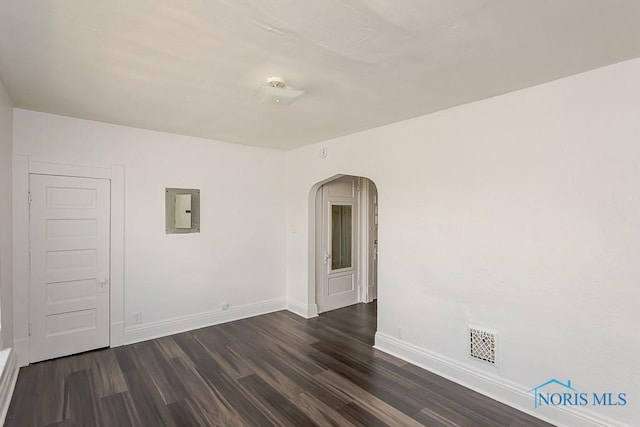 708 Spencer St, Toledo, OH 43609 - unfurnished room featuring electric panel, arched walkways, and dark wood finished floors