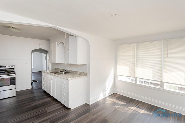 708 Spencer St, Toledo, OH 43609 - kitchen with stainless steel electric range, arched walkways, dark wood-style floors, and white cabinetry