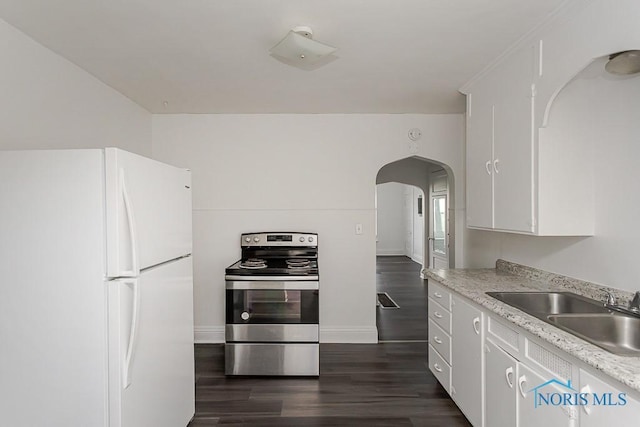 708 Spencer St, Toledo, OH 43609 - kitchen featuring freestanding refrigerator, stainless steel electric stove, arched walkways, dark wood finished floors, and white cabinetry