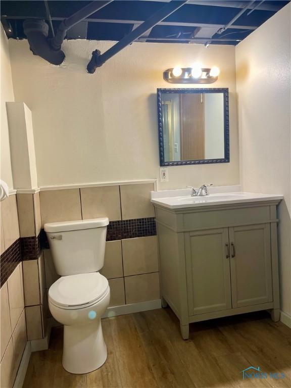 4846 Amesbury Rd, Toledo, OH 43612 - bathroom featuring wood finished floors, vanity, tile walls, and wainscoting