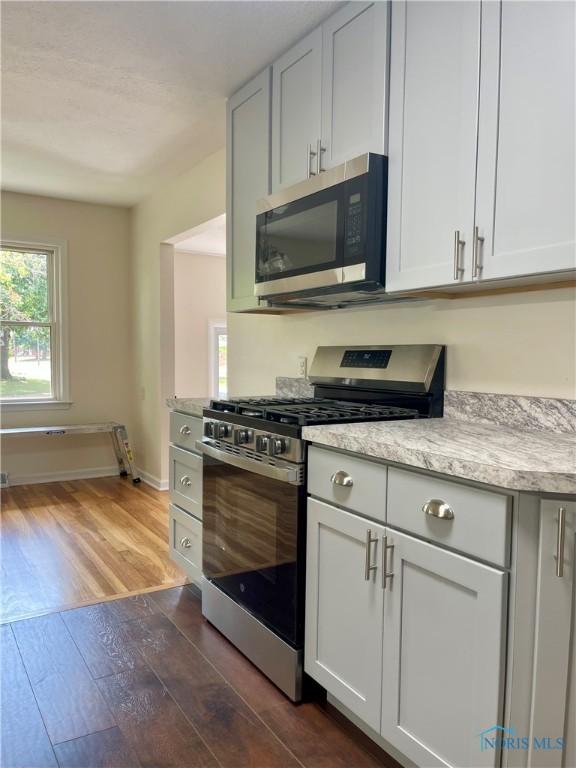 4846 Amesbury Rd, Toledo, OH 43612 - kitchen featuring stainless steel appliances, wood finished floors, and light stone counters