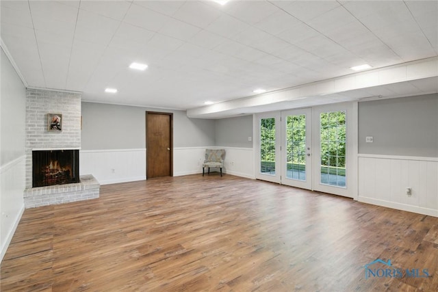 12982 State Route 34, Bryan, OH 43506 - unfurnished living room featuring a brick fireplace, wood finished floors, and a wainscoted wall