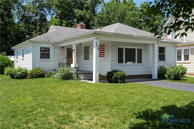 3328 Island Ave, Toledo, OH 43614 - bungalow with covered porch, a shingled roof, a front lawn, and a chimney