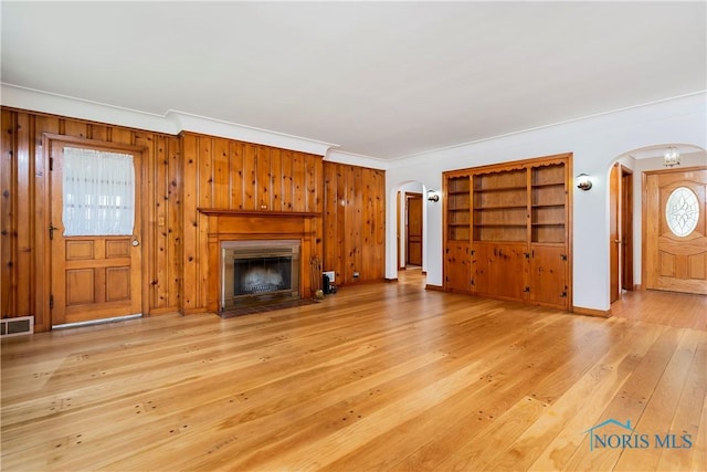 3328 Island Ave, Toledo, OH 43614 - unfurnished living room featuring arched walkways, crown molding, a fireplace with flush hearth, light wood-style flooring, and wooden walls