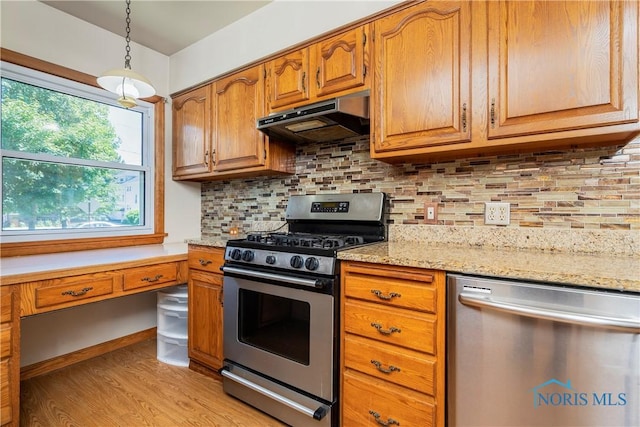 3328 Island Ave, Toledo, OH 43614 - kitchen with stainless steel appliances, under cabinet range hood, light wood-type flooring, brown cabinets, and pendant lighting