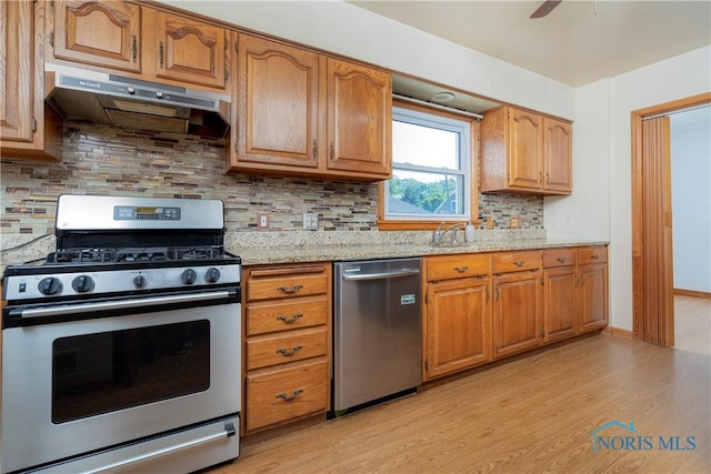 3328 Island Ave, Toledo, OH 43614 - kitchen with appliances with stainless steel finishes, under cabinet range hood, light wood-type flooring, light stone counters, and brown cabinets