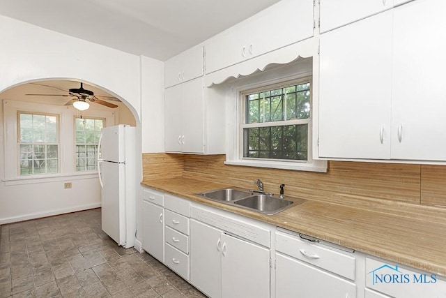 2529 Greenbriar Rd, Toledo, OH 43607 - kitchen with freestanding refrigerator, decorative backsplash, arched walkways, white cabinetry, and light countertops